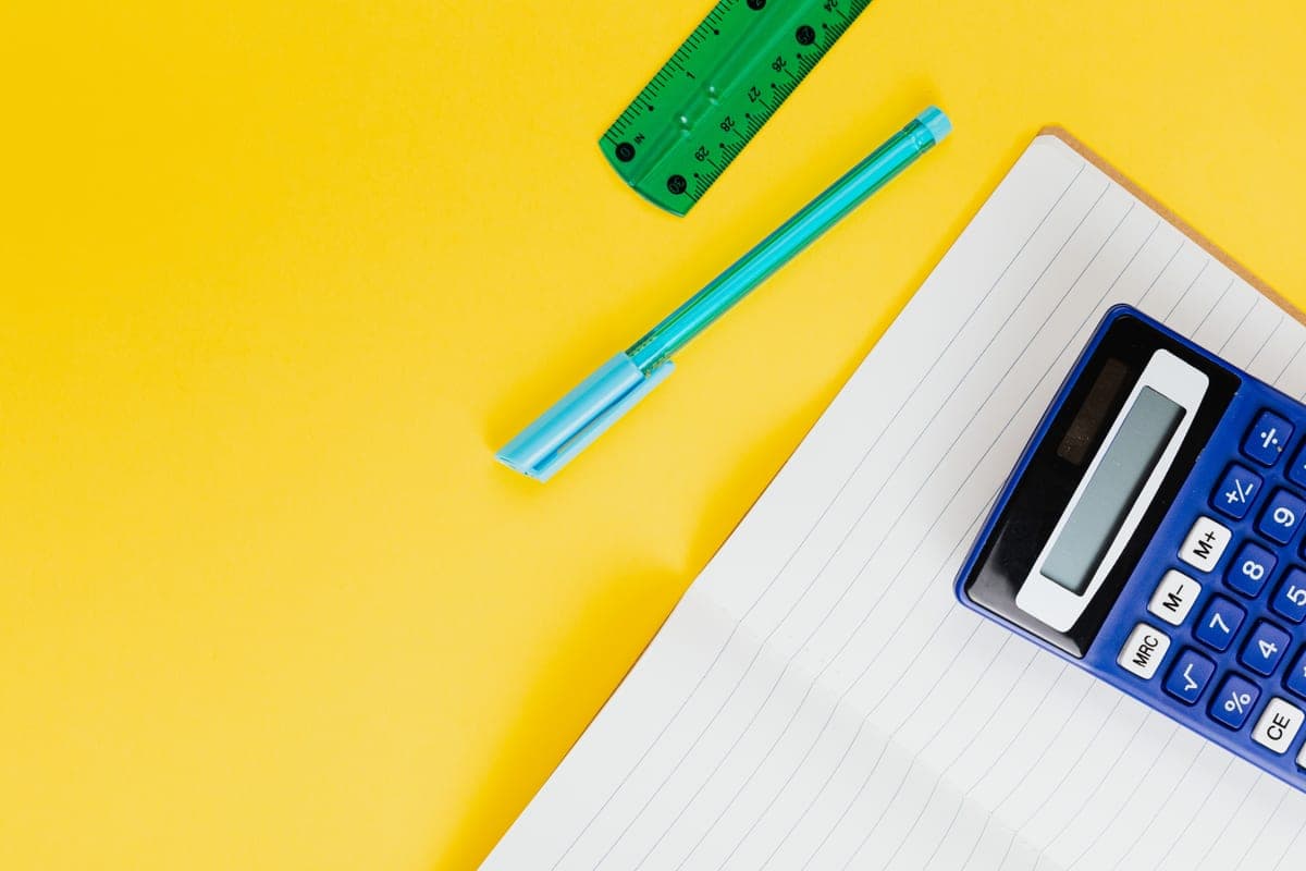 A desk with a notebook, pen and calculator