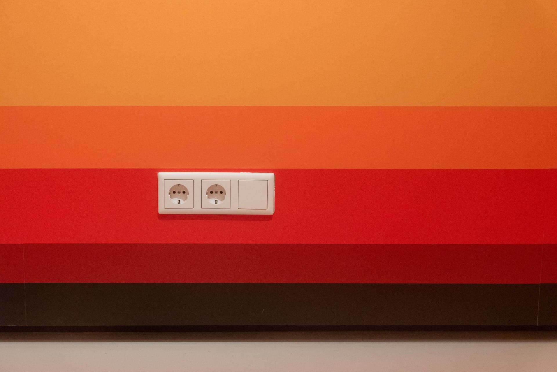 A pair of electrical sockets on a colored wall