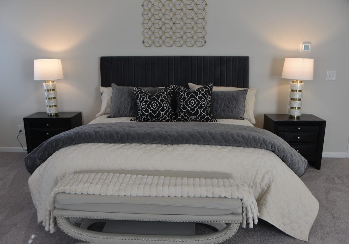 A neatly made bed with a heavy gray blanket in a minimal bedroom