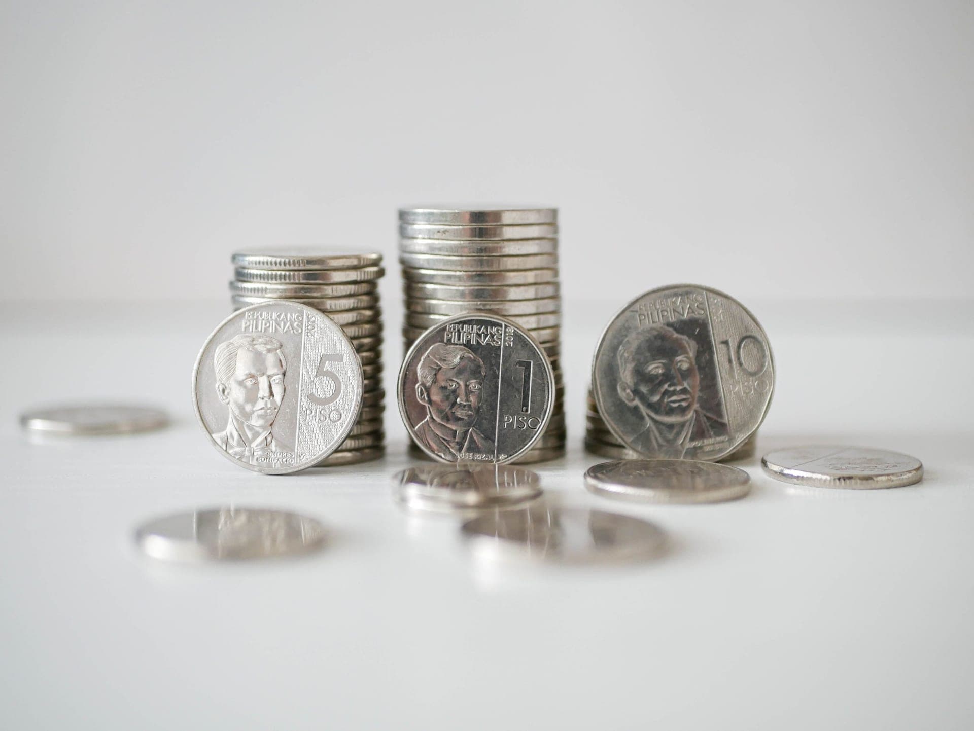 A close-up of stacked coins on a pale surface