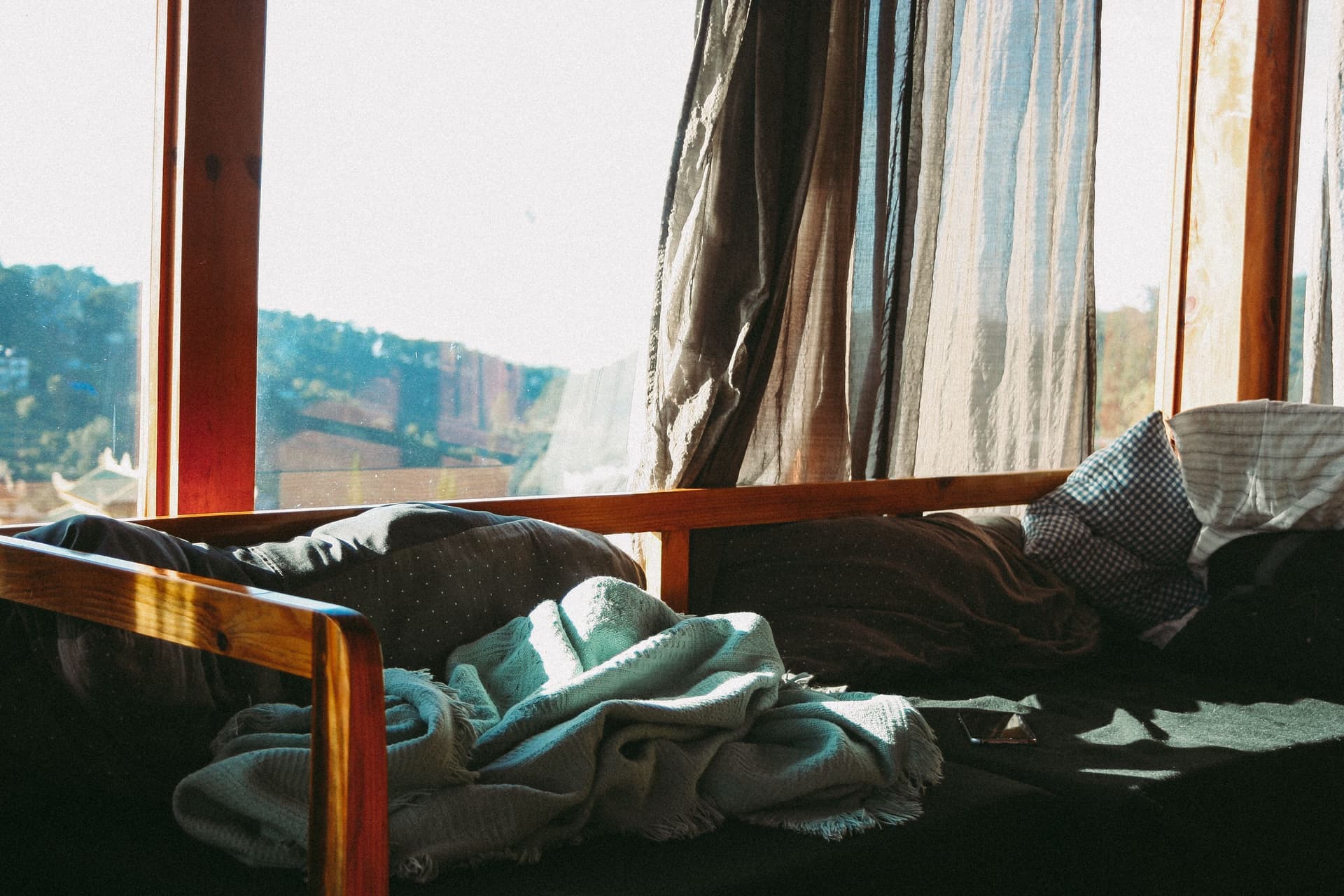 Sunlight falling across a bed layered with blankets and pillows