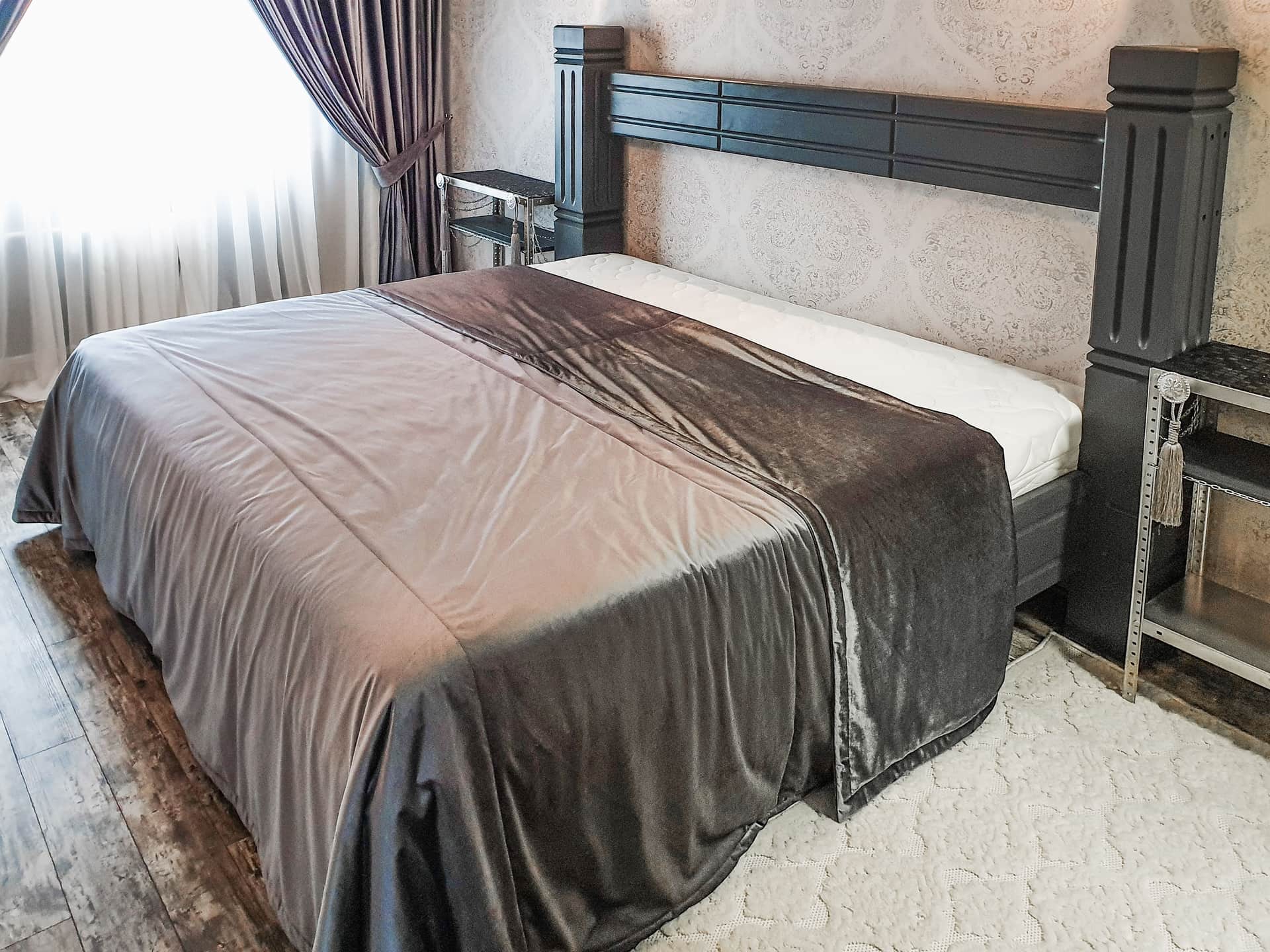 A bed dressed with a textured gray cover in warm light