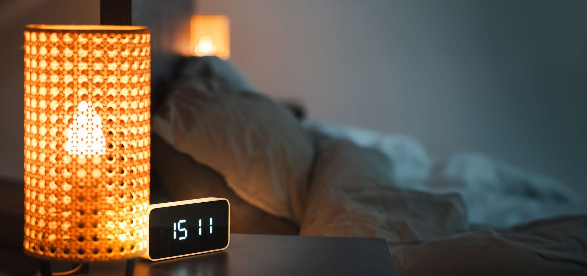 A digital alarm clock glowing in a dim bedroom