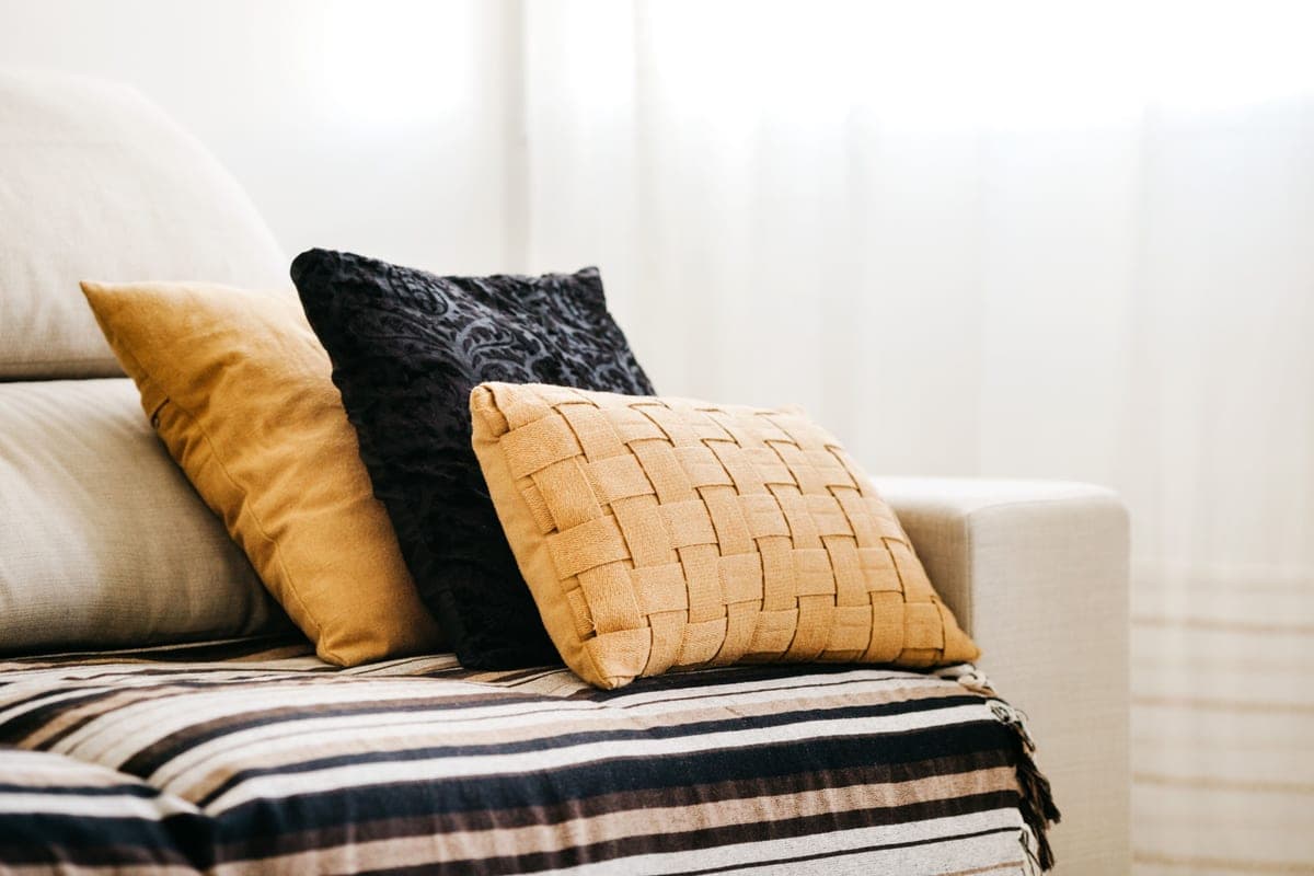A living room sofa with cushions and a folded throw