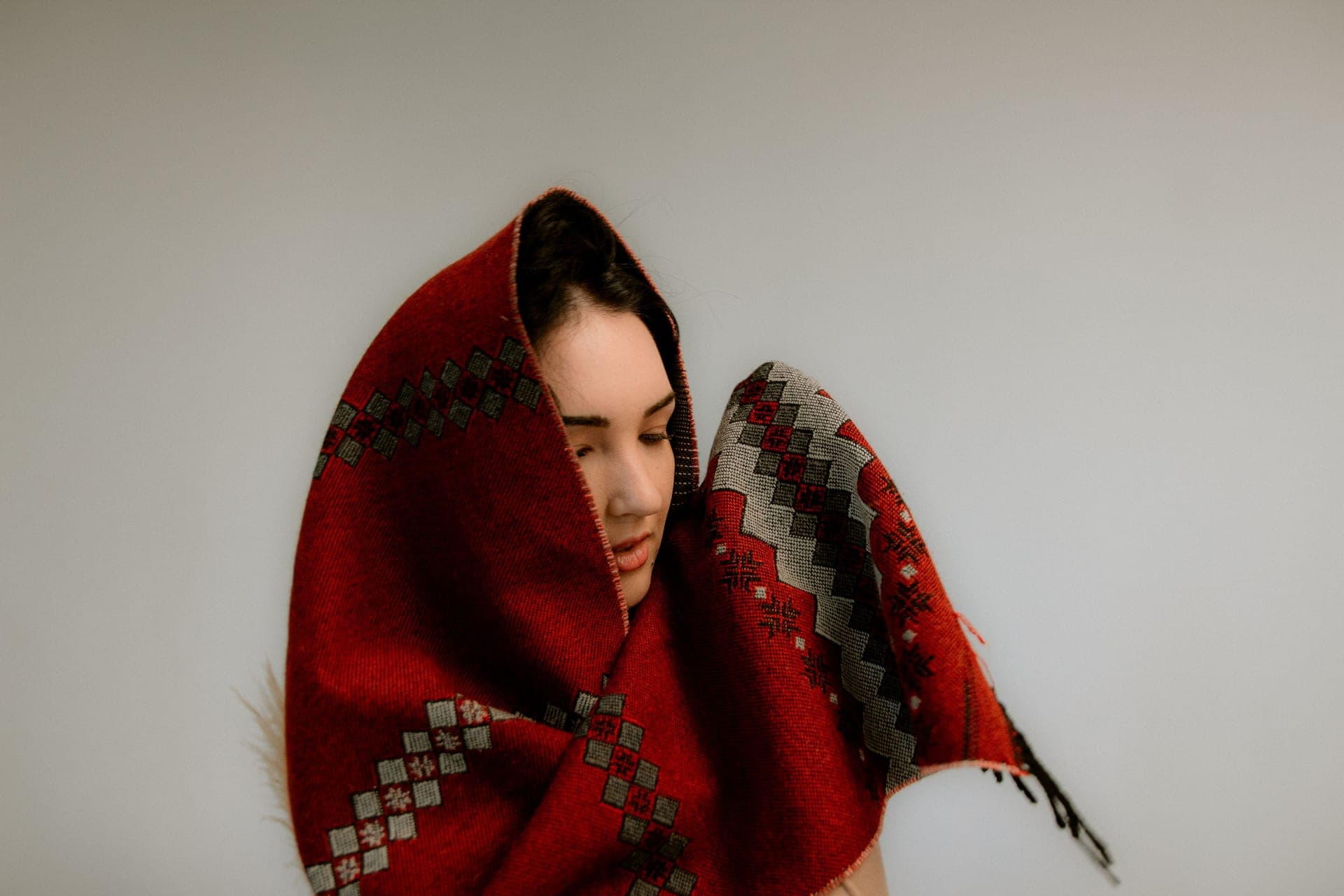 A person draped in a patterned red shawl