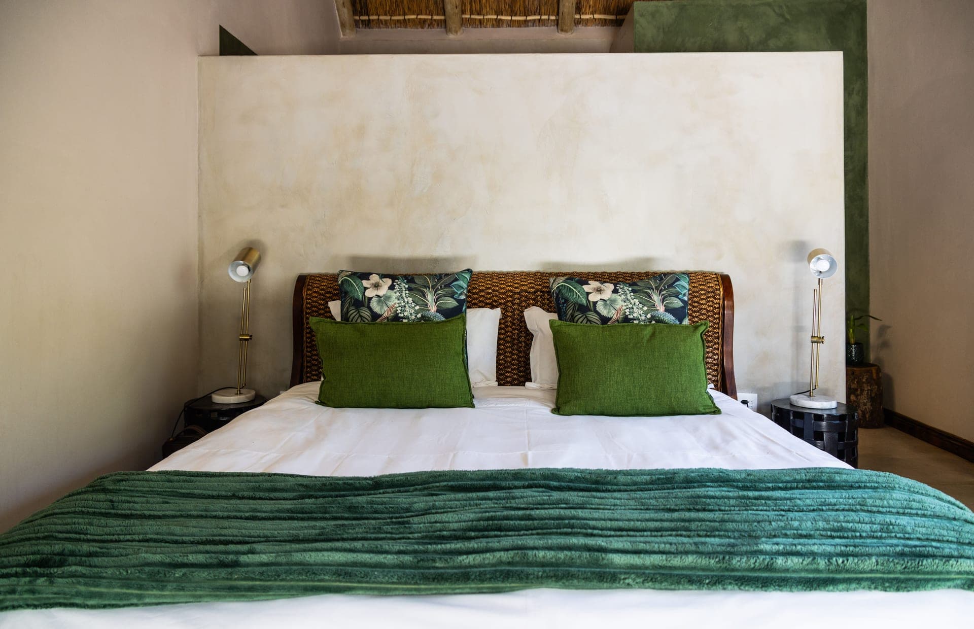 A wide bed dressed in white with a folded throw across the foot