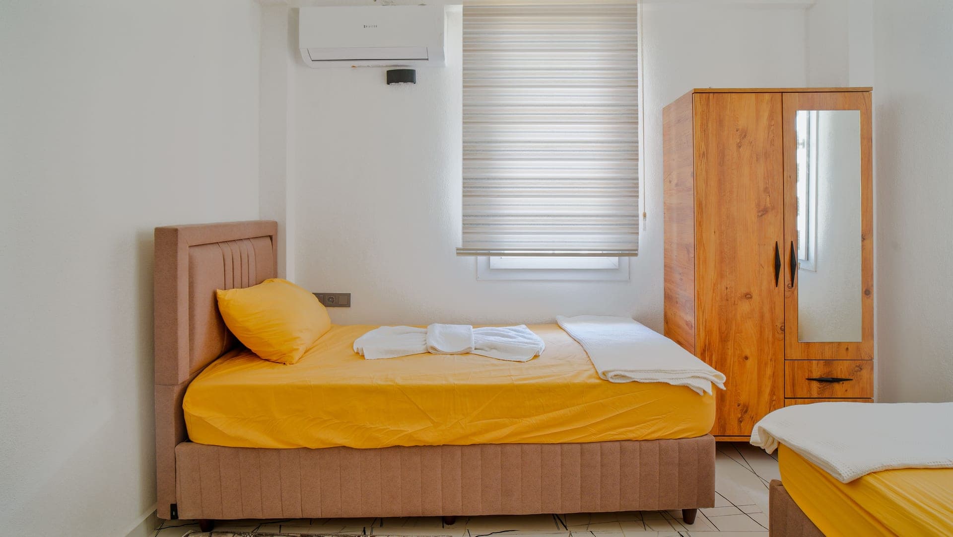 A minimalist bedroom with a single bed and a wooden wardrobe