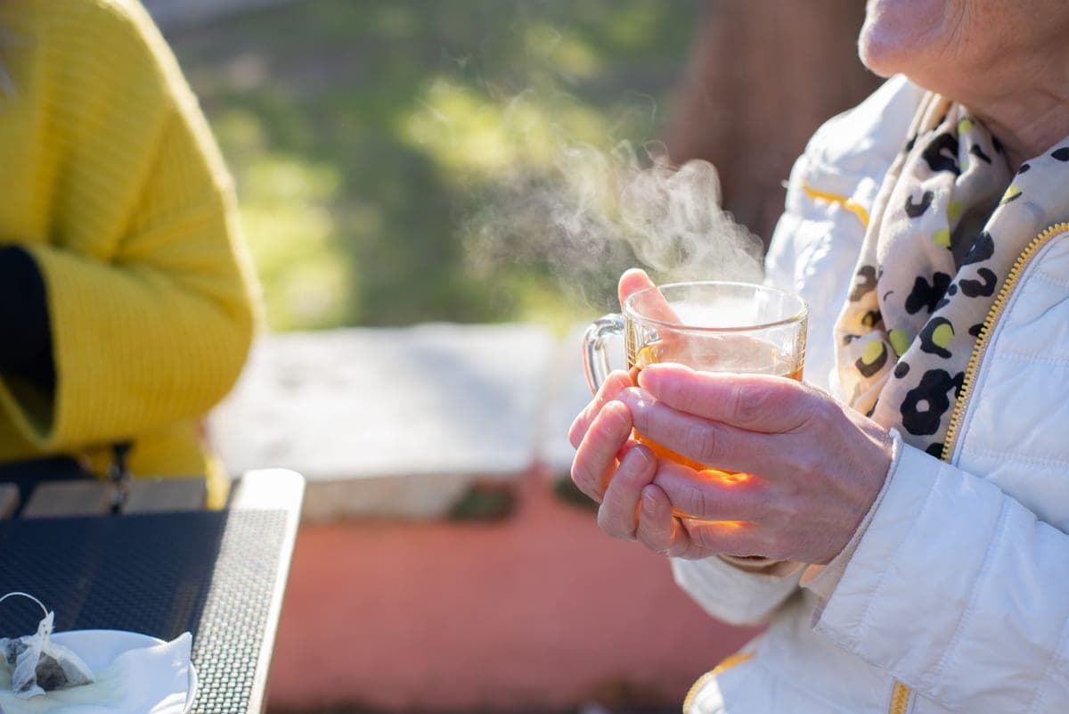 An older person's hands holding a warm mug