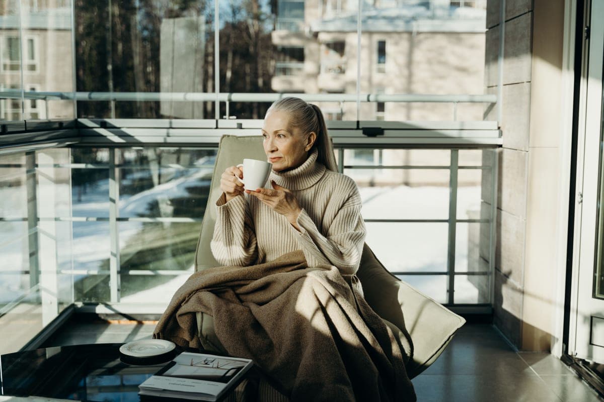 An older person sitting in an armchair with a blanket