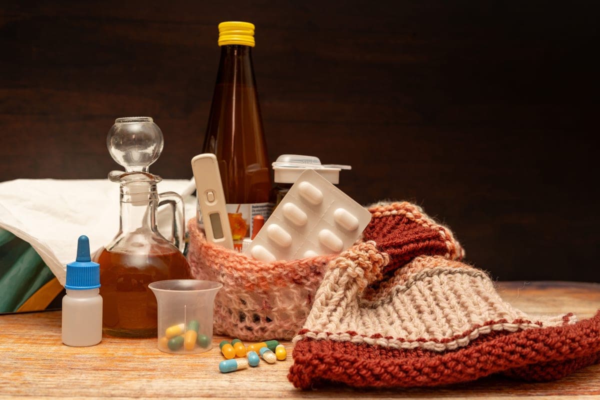 A hot water bottle in a knitted cover resting on a bed