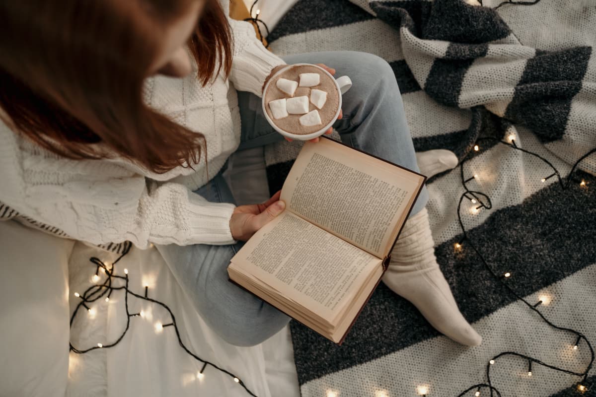 A person reading under a blanket on a winter evening