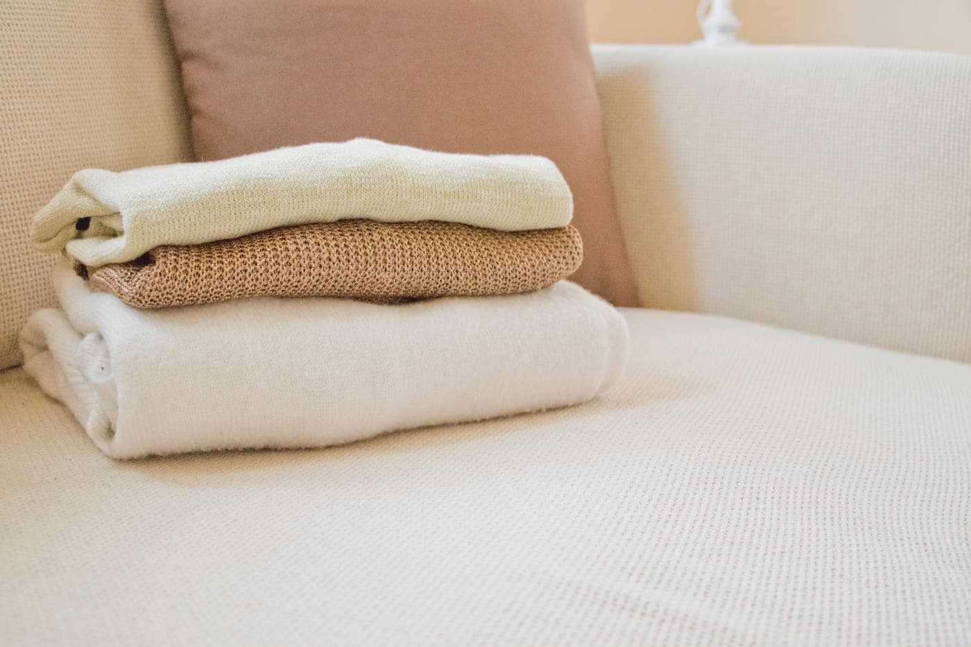 A folded throw blanket over the arm of a sofa in evening light
